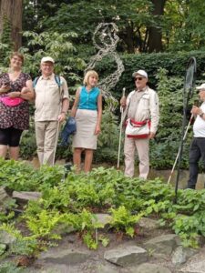 Grupa osób z białymi laskami wśród zieleni ogrodu botanicznego