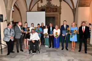 zdjęcie grupowe z prezydentem Wrocławia. W rękach ludzie trzymają kwiatek