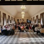 duża sala pelna ludzi siedzących przy stołach